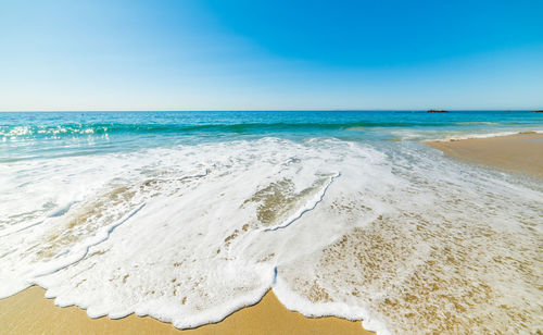 Scenic view of beach against clear blue sky