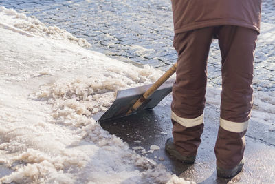 Man with snow shovel cleans city sidewalk in winter.