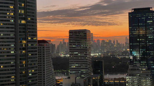 Illuminated buildings in bangkok city against sky during sunset