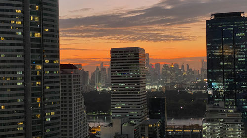 Illuminated buildings in city against sky during sunset