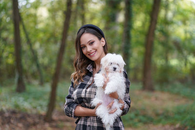 Portrait of a smiling young woman with dog in the forest