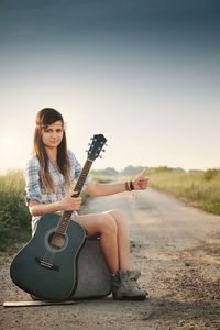 Young woman sitting on guitar