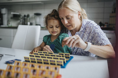 Mother and daughter spending time together playing game at home