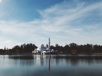 View of church at waterfront against cloudy sky