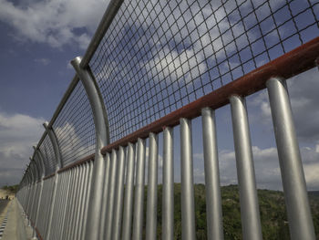 Low angle view of metal fence against sky