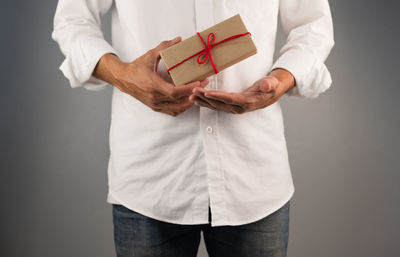 Midsection of man holding hands against white background