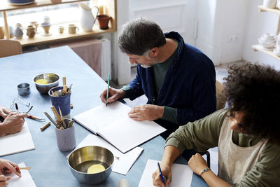 High angle view man and woman drawing at table during art class