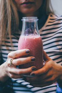 Midsection of woman holding bottle with smoothie