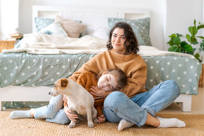 Happy mom and daughter play with their adorable wired jack russell terrier