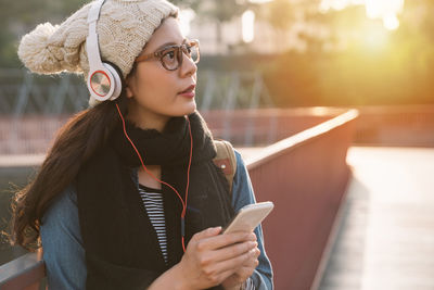 Close-up of young woman listening to music on footpath