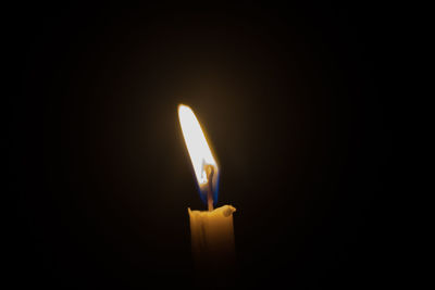 Close-up of burning candle in darkroom