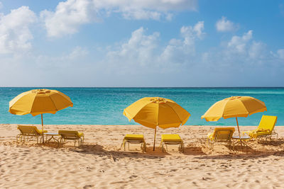 Deck chairs on beach against sky