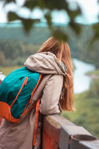 Rear view of woman leaning on railing