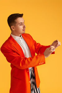 Young woman standing against yellow background