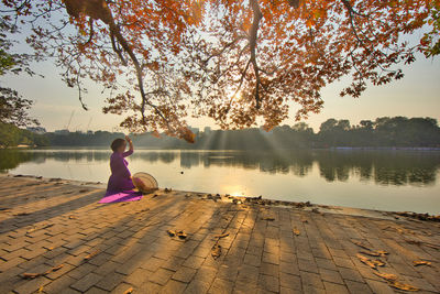 Rear view of woman standing by lake