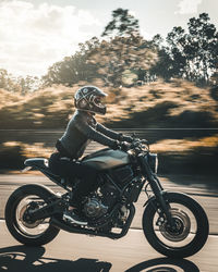 Man riding motorcycle on road against sky during sunset