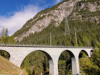 Arch bridge over mountains against sky