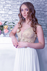 Portrait of beautiful young woman standing against wall