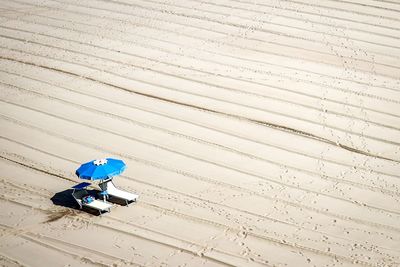 High angle view of lounge chairs with umbrella on sand