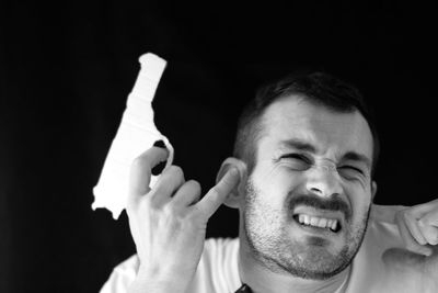 Shirtless man attempting suicide with gun against black background