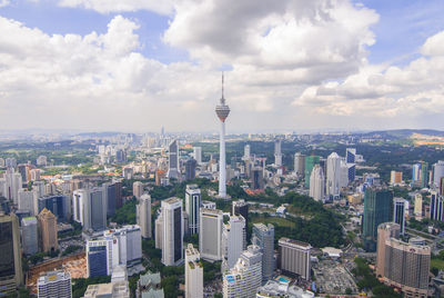 Aerial view of buildings in city against cloudy sky