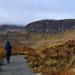 Rear view of man walking on mountain against sky
