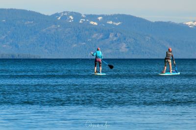 Men standing in sea against sky