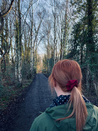 Rear view of woman with a ponytail walking in woodlands