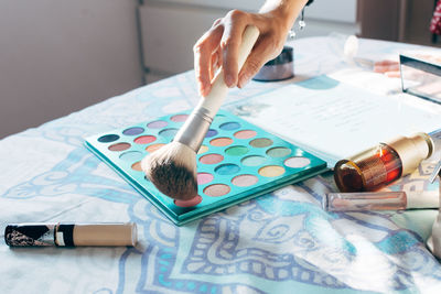 Unrecognizable crop female makeup artist applying eyeshadows with brush while working in beauty salon