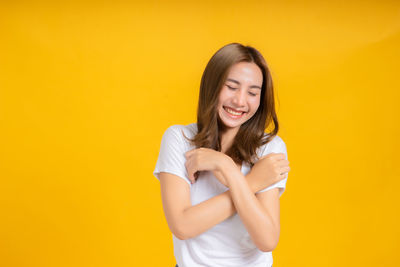 Young woman smiling against yellow background