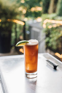 Tamarind whiskey sour in tall collins glass with lime wedge