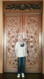 Full length of woman standing against door at home