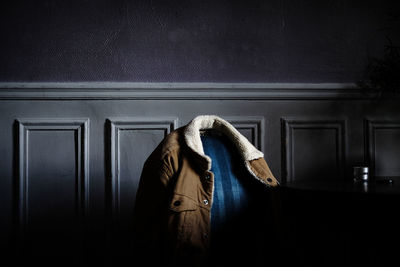 Close-up of jacket on chair against wall at home