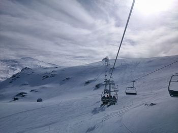 Ski lift over snowcapped mountains against sky