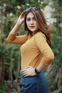 Young woman standing against trees