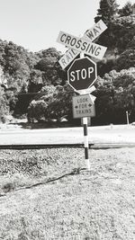 Road sign by railroad tracks against sky