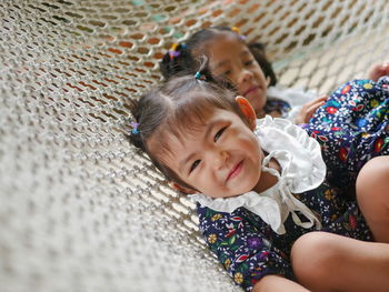 Asian baby girl enjoys lying down on a hammock together with her older sister at home