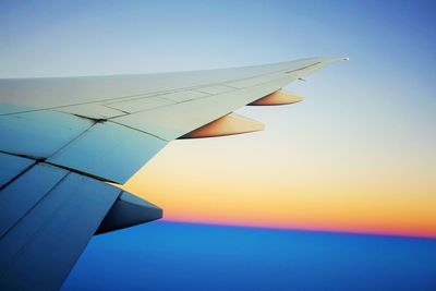 Airplane wing against sky during sunset