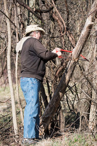 Low section of man trimming bare trees in forest