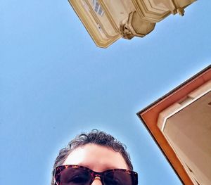 Low angle portrait of man against clear blue sky