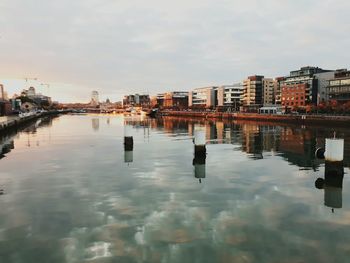 Reflection of cityscape in river against sky