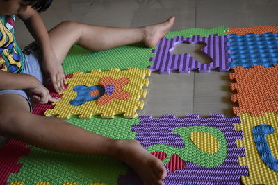 High angle view of boy playing with colorful mats on floor
