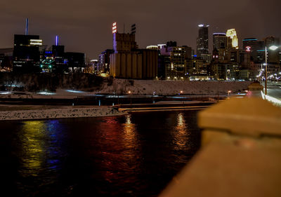 River in front of illuminated buildings at dusk