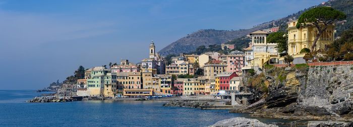 Buildings by sea against sky in town