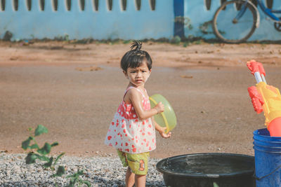 Portrait of cute girl holding plastic container in back yard