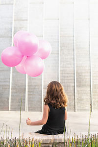 Rear view of woman with pink balloons