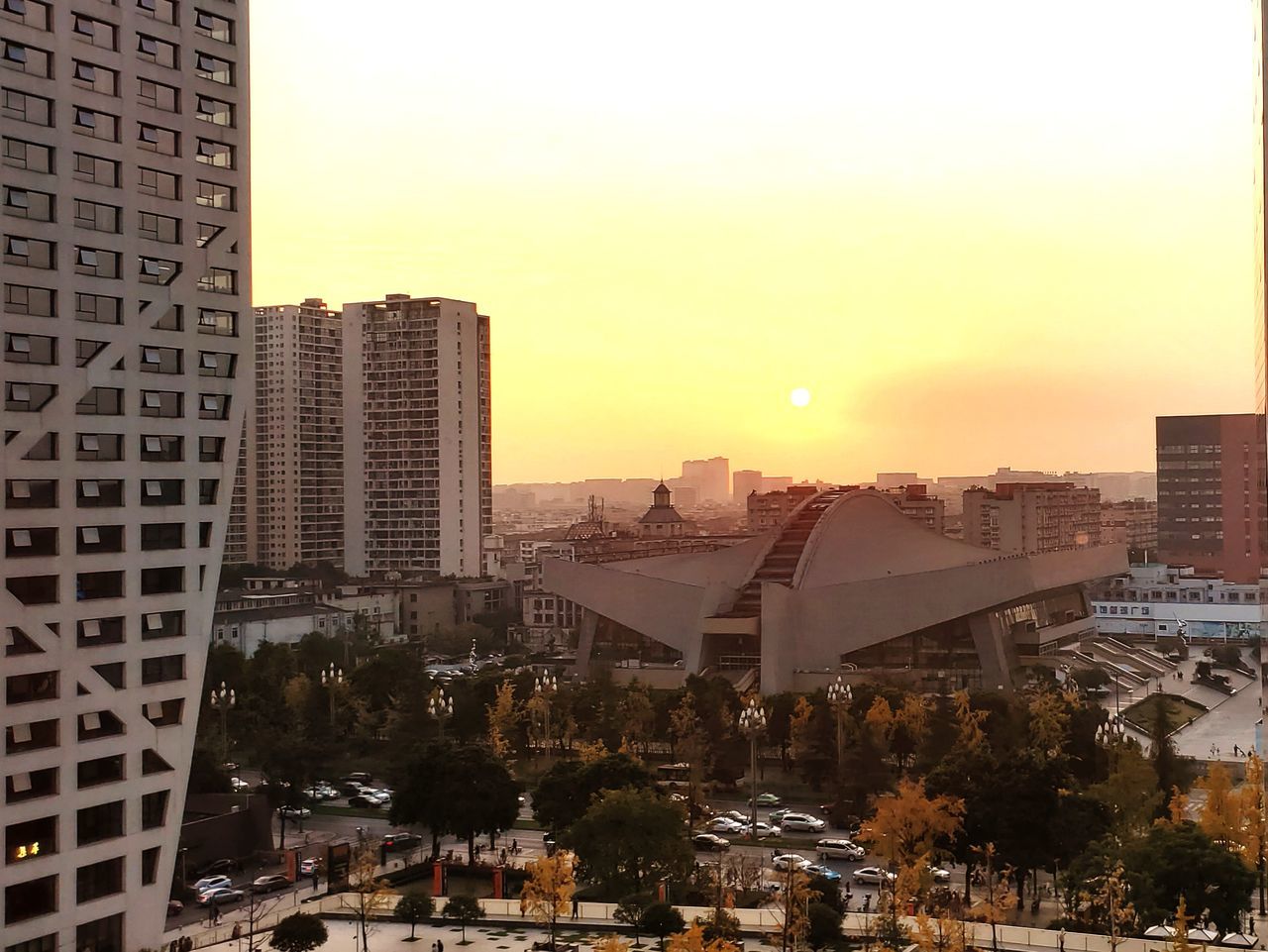 building exterior, architecture, built structure, city, sky, building, sunset, nature, residential district, cityscape, no people, office building exterior, outdoors, city life, plant, tree, skyscraper, orange color, street, clear sky