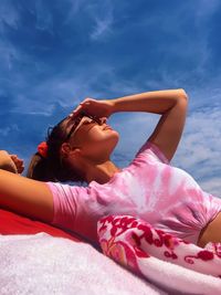 Young woman lying down outdoors against sky