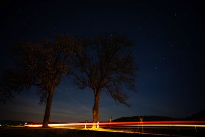 Light trails on street against sky at night