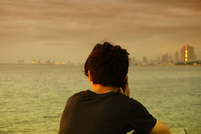 Rear view of man in sea at sunset